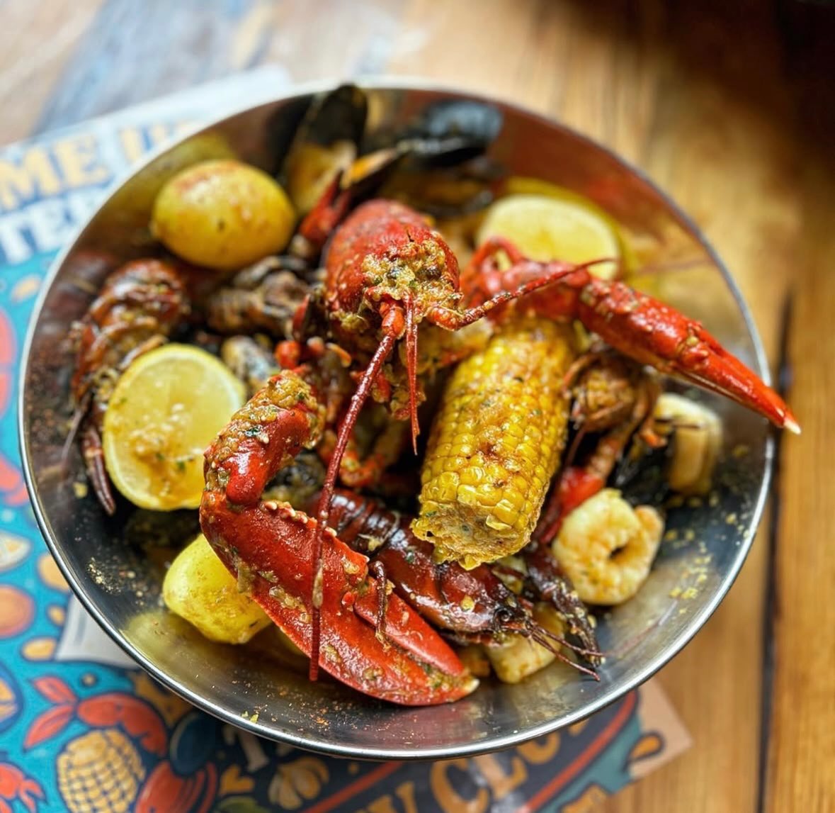 A whole lobster on a Claw Club seafood boil with prawns, mussels and corn