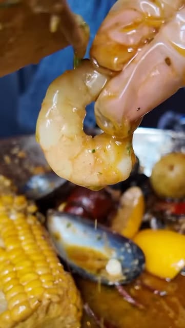A buttery prawn lifted from a seafood boil